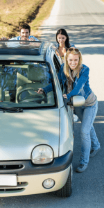 Three young people pushing a car